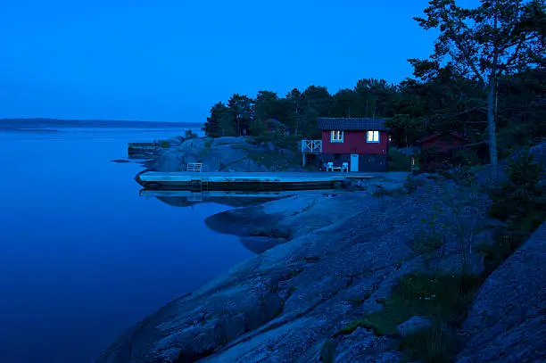 A red cottage in the Stockholm archipelago during the blue hour, just after sunset.