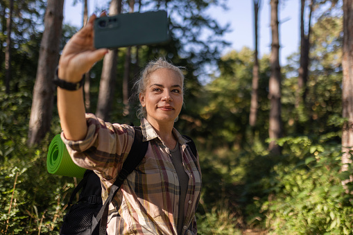 Beautiful female hiker taking a selfie with the smart phone in nature