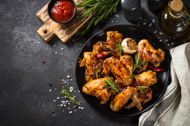 istock Grilled chicken wings with spices at black table. 1682708943