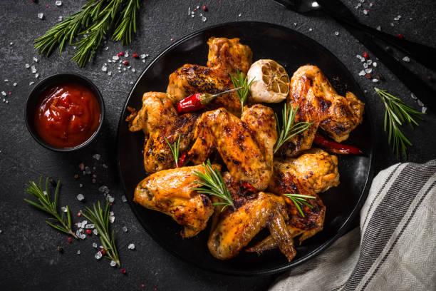 istock Grilled chicken wings with spices at black table. 1682708971