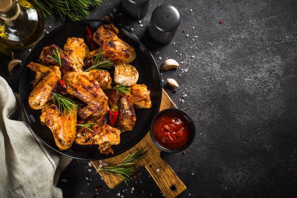 istock Grilled chicken wings with spices at black table. 1682708992