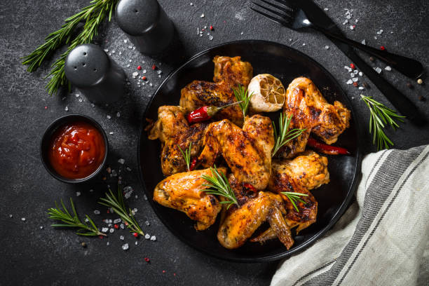 istock Grilled chicken wings with spices at black table. 1682710091