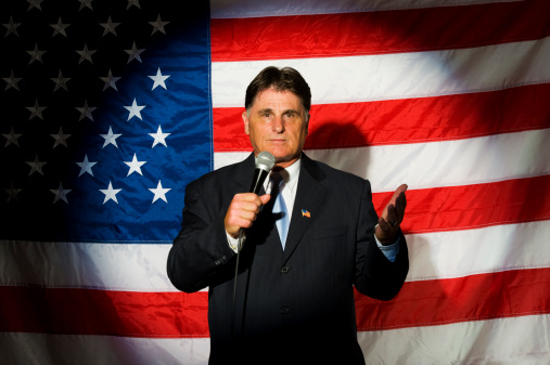 A spotlight on a politician giving a speech against an American flag