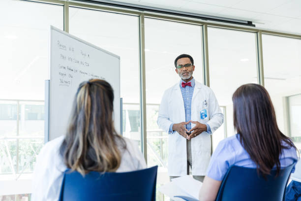 médico maduro concentra sua atenção na estudante de medicina irreconhecível - male black medical student mature student - fotografias e filmes do acervo