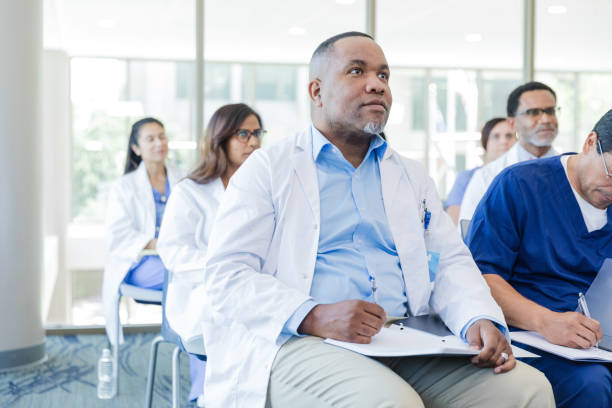 médico maduro se concentra em falante invisível - male black medical student mature student - fotografias e filmes do acervo