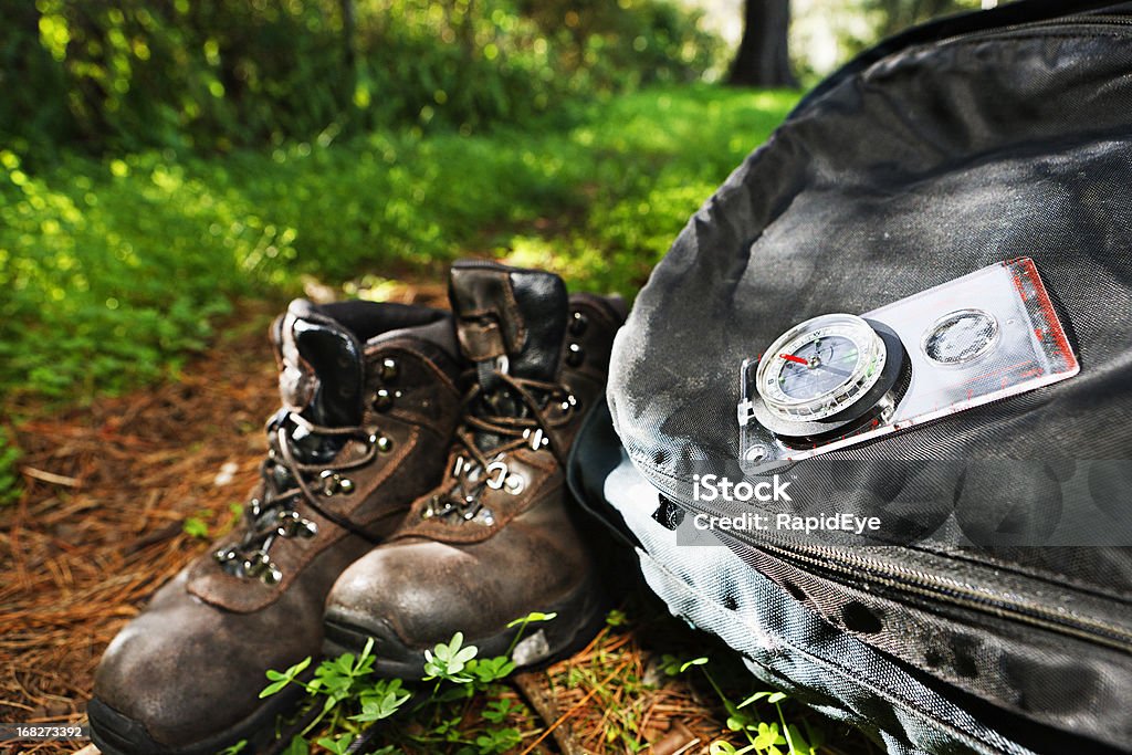 Randonnée à thème: Bottes, sac à dos et boussole sur radieux Sentier forestier - Photo de Camping libre de droits