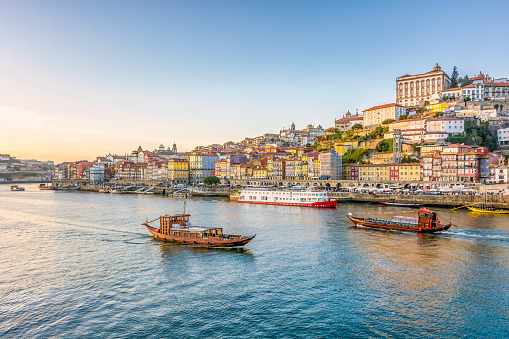 Scenic view of the city of Porto in Portugal in warm winter sunset light with boats and Douro river in foreground