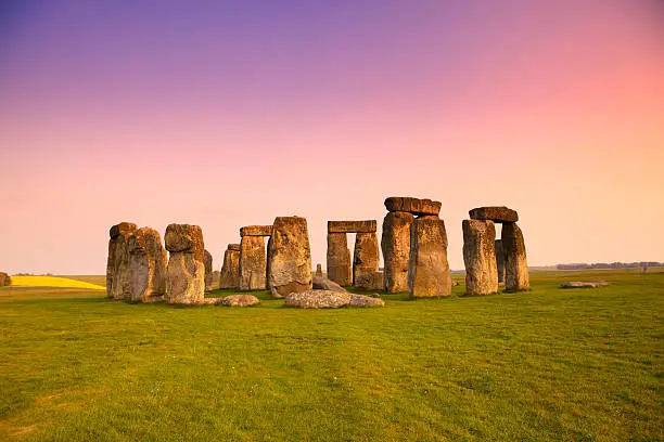 Ancient stones at UNESCO World Heritage Site at Stonehenge, Wiltshire, UK. Dramatic sky and golden hues of dusk. Major tourist destination, archeological and pilgrimage site during Summer Solstice and Winter Solstice.