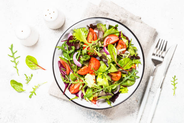 istock Green salad with fresh vegetables at white. 1682760871
