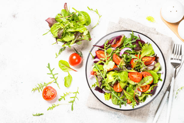 istock Green salad with fresh vegetables at white. 1682760886