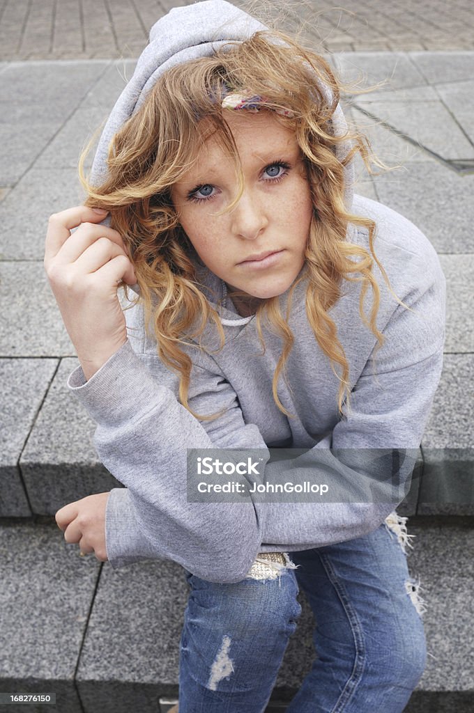 Street Teen Young female teenager, sitting outdoors, looking sad. 14-15 Years Stock Photo