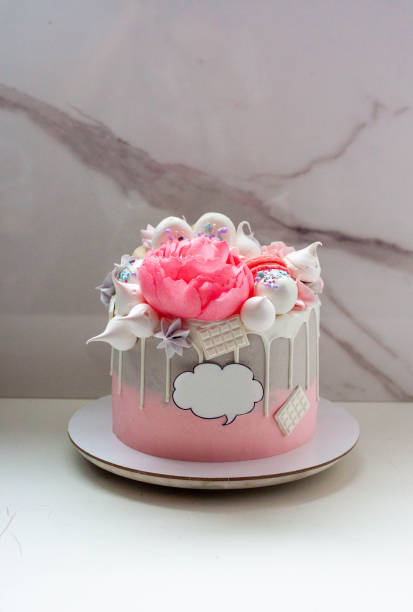 istock Beautiful and elegant grey and pink cake decorated with melted white chocolate, macaroons, edible peony flower and meringue kisses 1682773594
