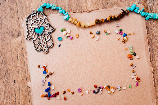 Horizontal flatlay mockup with very small healing stones and a  fatima hand on brown hand made paper. Copy space. Very well suited for designs for spiritual magazines in digital or printed versions. Part of a series.