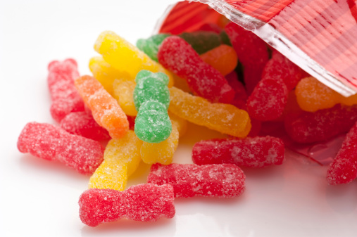 colorful assorted gummy candies coming out of the bag on white background