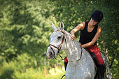 A girl on a gray horse in the forest in Norway