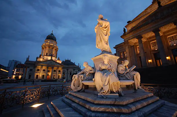 Konzerthaus and German cathedral at Gendarmenmarkt in Central Berlin (Germany), In front statue of Friedrich Schiller, German Poet. night time photography