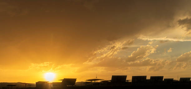 ciel captivant au coucher du soleil avec des panneaux solaires face au soleil - superbe photo d’archives - dramatic sky dusk night sustainable resources photos et images de collection