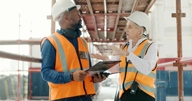 istock Construction, inspection and man with checklist talking to woman in engineering on site with scaffolding and building renovation. Contractor, survey and list of industrial maintenance safety rules 1682817056