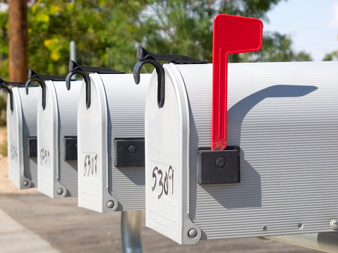 mailboxes in a row, one with red flag up.  horizontal composition and selective focus on foreground.