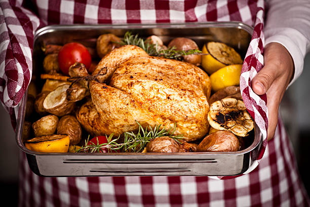 Roasted Chicken with Vegetables in Roasting Tin Young woman holding roasting tin with roasted chicken cooking pan photos stock pictures, royalty-free photos & images