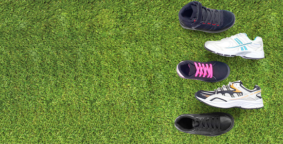 Group of running assorted athletic shoes for the family on a green grass