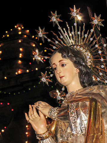 Spiritual statue of crowned woman on black background, representing Christianity and immaculate conception.