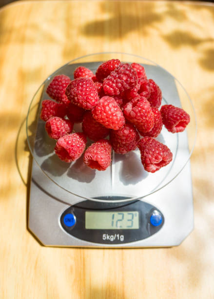 Close-up picture of a pile of fresh raspberries on a white table, white background, no people, healthy summer snack, organic nordic berries, flat lay image, sweet juicy berries, focus on details