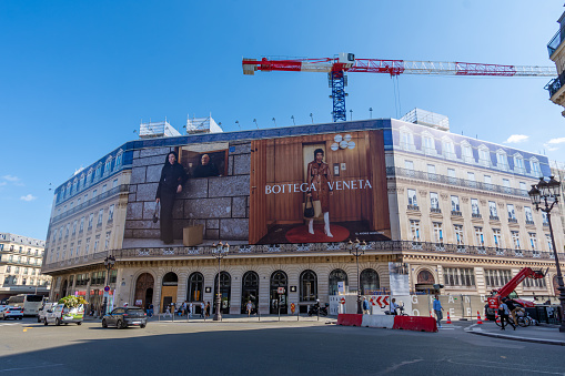 Paris, France - September 15, 2023: Bottega Veneta giant advertising billboard covering the scaffoldings of the restoration works on the facade of a parisian building