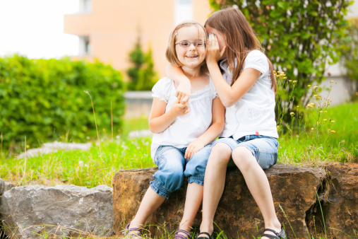 a girl is telling her little sister a secret