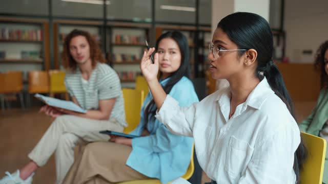 Serious Indian female student answering during a class in library