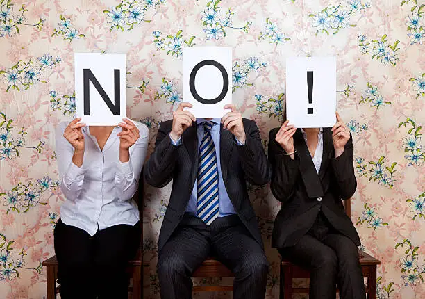 Photo of Three people holding the word NO! over their faces