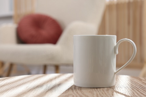White mug on wooden table indoors, space for text