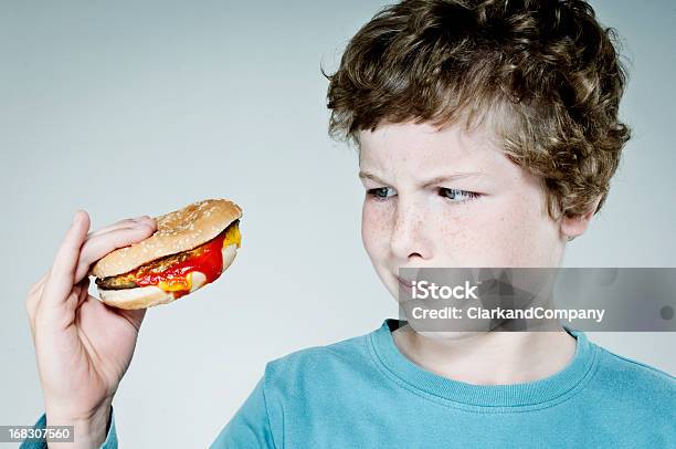 Молодой Мальчик Держа Гамбургер Всматриваться На Ит — стоковые фотографии и другие картинки Грусть