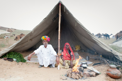 Husband and wife sit outside their tent at Pushkar Camel Fair.