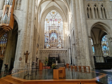 Inside the famous Cathedral of St. Gudula (Cathedral of St. Michael and St. Gudula) in Brussels. It is a medieval Roman Catholic cathedral in central Brussels, Belgium. The church was built between 11th–15th centuries. The image shows some columns and a large window in the chruch.