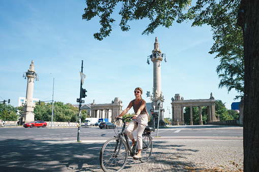 Woman cycling in Berlin with Charlottenburg Gate in background Germany