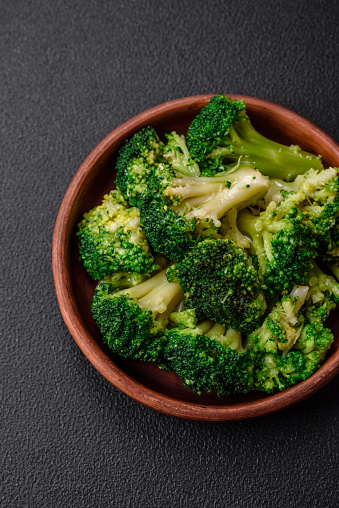 Delicious fresh green broccoli steamed in a ceramic plate on a textured concrete background