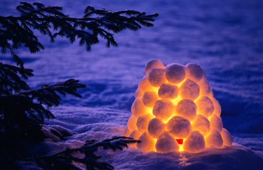 Snow lantern beside spruce tree in winter evening. Scanned from film.