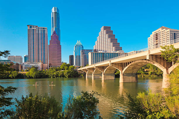 golden hour light illuminates Stand up Paddleboarders on Ladybird Lake and Congress Avenue Bridge, Austin Texas skyline