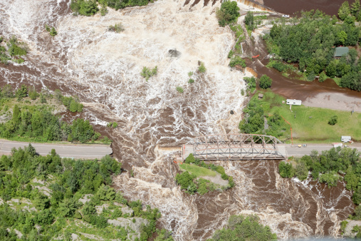 Aerial view of a two lane road washed away from storm floodwater with a truss bridge to the right. A stranded car is in the upper right  Shot from the open window of a small airplane. http://www.banksphotos.com/LightboxBanners/Aerial.jpg