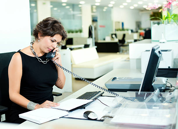 Woman in black dress speaking on phone on office Business woman talking over the phone in Office hotel reception hotel service technology stock pictures, royalty-free photos & images