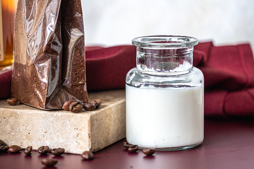 A tiny jar of milk on red table and pack of coffee on marble stone. Copy space. High quality photo