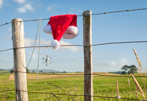 Christmas in summer - a red santa hat and decorations on a rustic fence in rural New Zealand, taken in December.