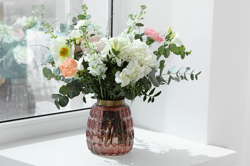 Bouquet of beautiful flowers on windowsill indoors