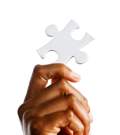 A woman's hand holds up a single jigsaw piece, isolated against a white background. The solution to the puzzle perhaps. 