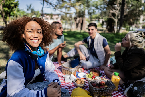 Portrait of a young woman on a picnic with his friends at the public park