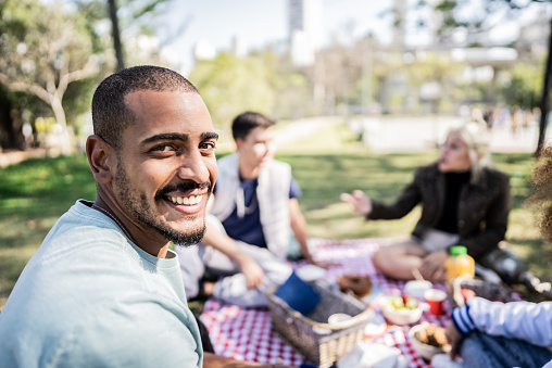 Portrait of a young man on a picnic with his friends at the public park
