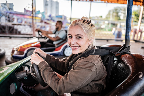 Portrait of a young woman having fun riding bumper car in the amusement park