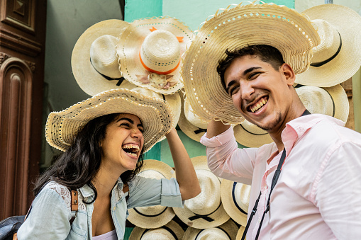 Young couple having fun while putting on sun hats outdoors