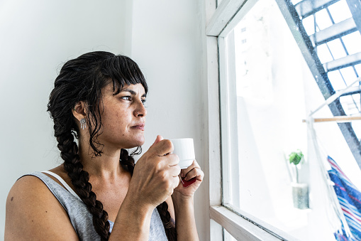 Mid adult woman contemplating while look through window at the home